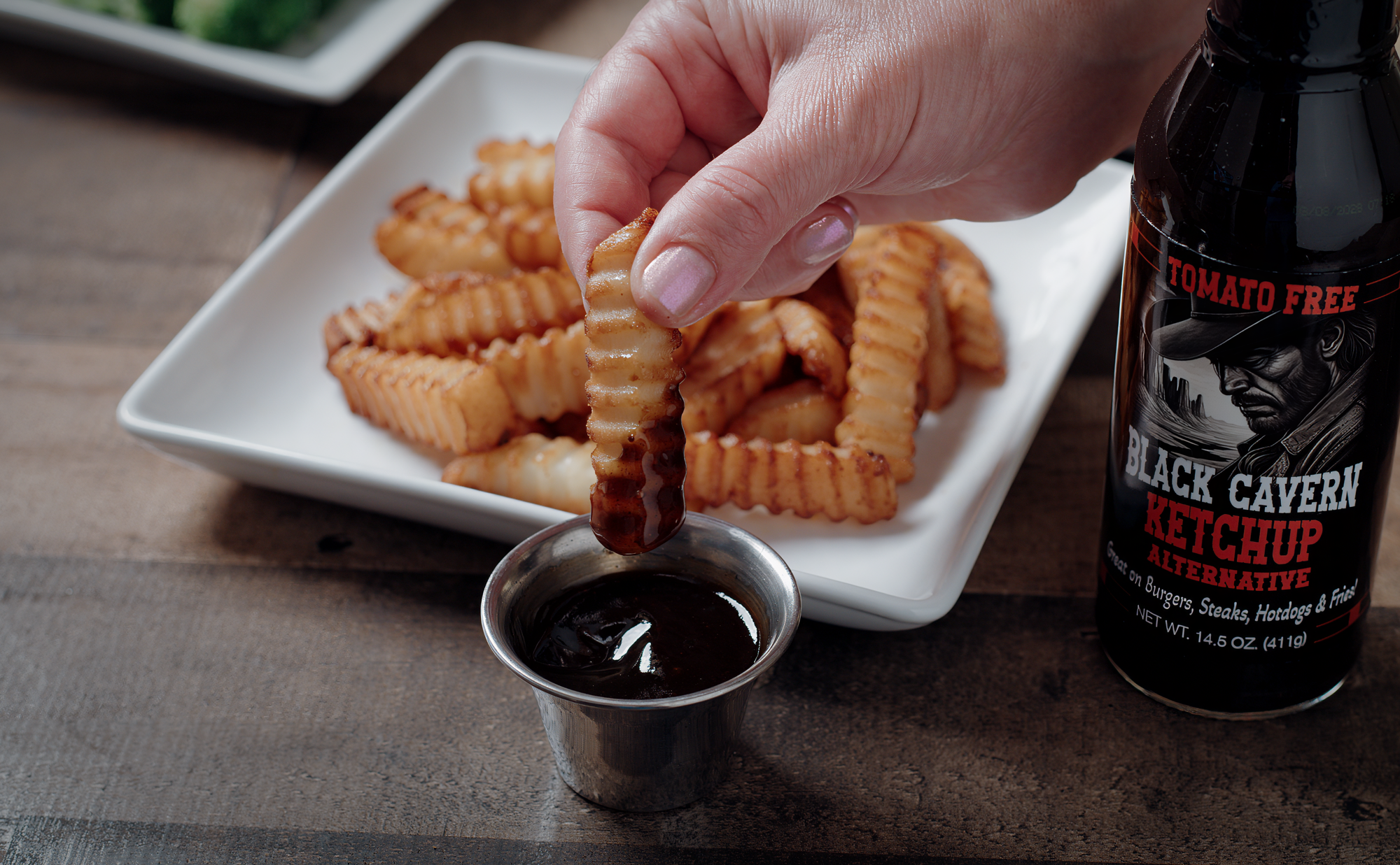 Crinkle fry being dipped into Black Cavern sauce